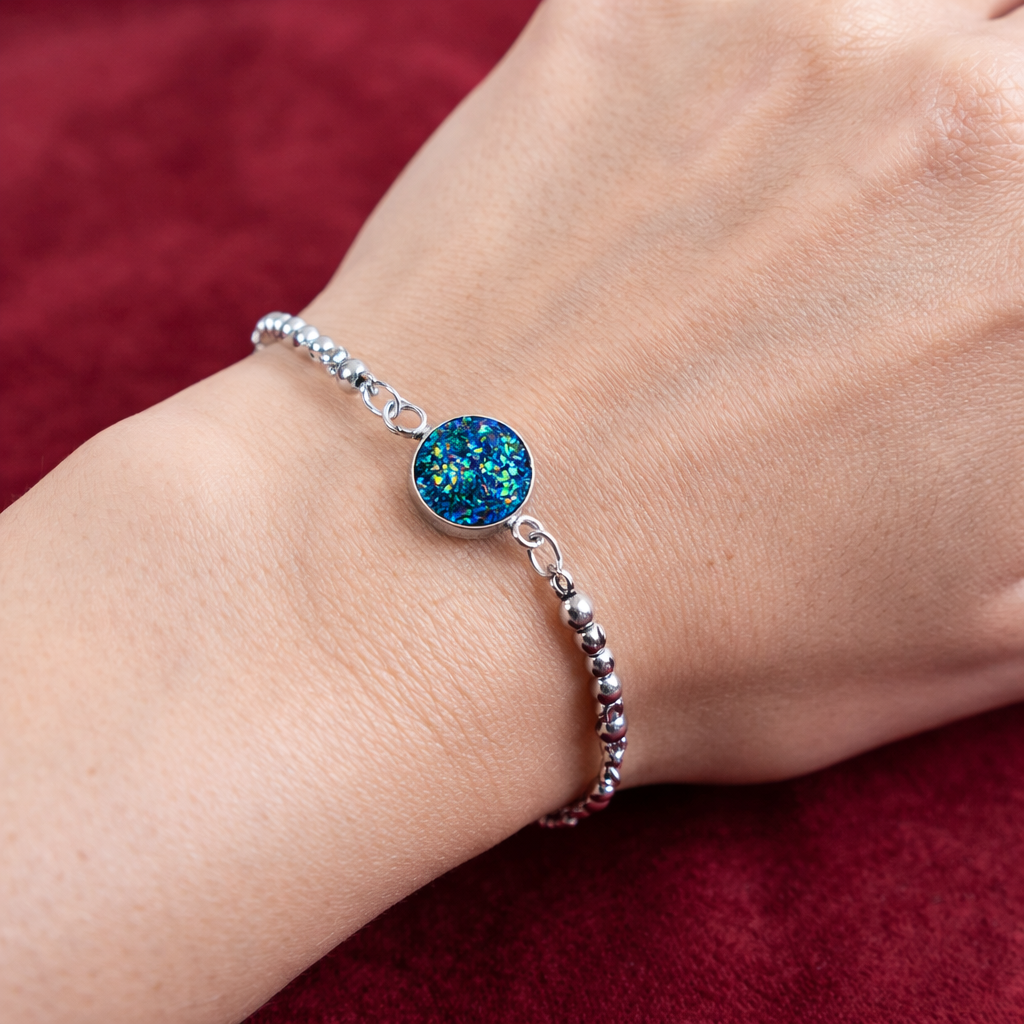 Bracelet en acier inoxydable argenté avec pendentif rond bleu scintillant porté au poignet
